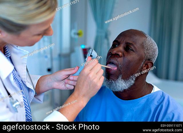 Caucasian female doctor examining throat of african american male patient