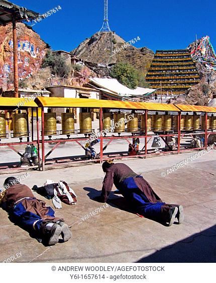 Buddhists prostrate themselves at 1000 Buddhas shrine on the Lingkor pilgrim way Lhasa Tibet