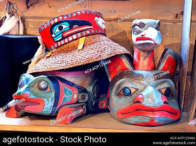 Haida-style straw hat on top of a Tlingi-inspired frog forehead mask. To the right is a Tlingit-inspired bear forehead mask in native art shop Deil'e