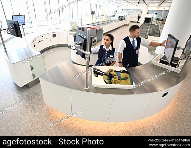 24 May 2023, Bavaria, Munich: ILLUSTRATION - Two security checkpoint employees check baggage in one of a total of five new installations at Munich Airport