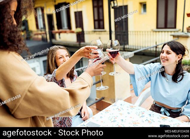 Female friends toasting wineglasses while sitting at terrace
