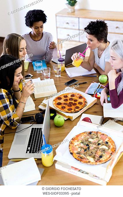 Group of young women at home studying and having pizza