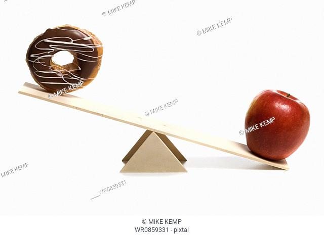 Close-up of a donut and an apple on a seesaw