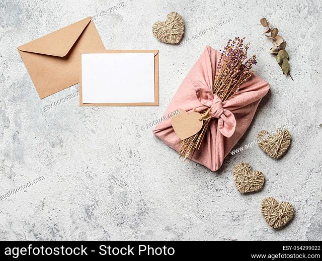 Zero waste Valentine's Day concept and mock up. Eco-friendly gift cloth wrapping in Furoshiki style, craft paper envelope, empty gift or greetings card