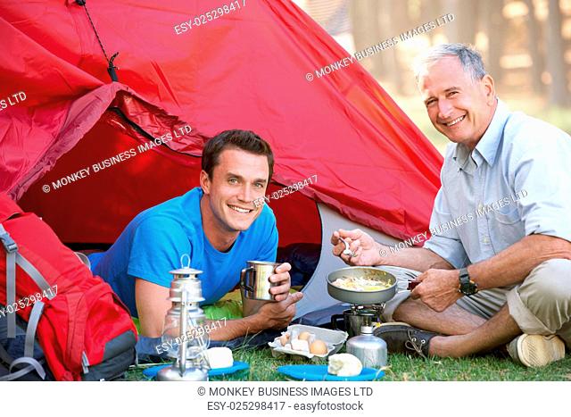 Father And Adult Son Cooking Breakfast On Camping Holiday