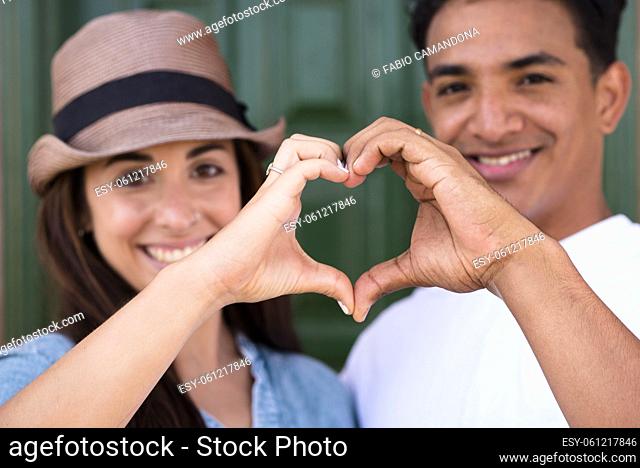 Portrait of happy couple making heart shape sign with hands. Happy adult couple falling in love making heart shape symbol with hands