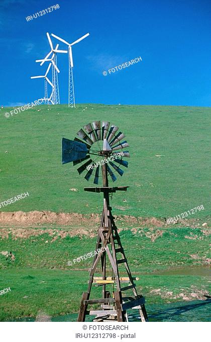 Wooden windmill in foreground with wind turbines