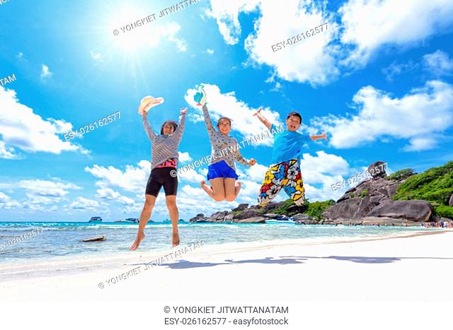 Family travels on vacation jumping with happy on beach near the sea under the sun blue sky and clouds of summer at Koh Similan Island in Mu Ko Similan National...