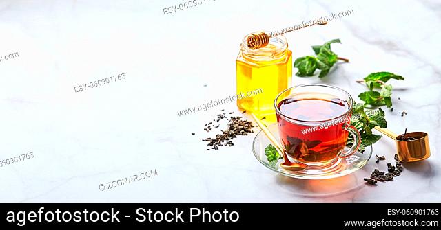 Black tea in glass transparent mug with mint leaves and honey. Calming and revitalizing tea, anti-stress and relaxation