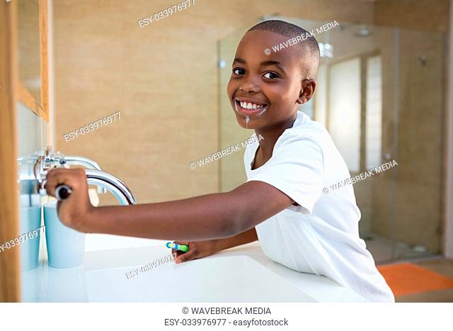Side view portrait of smiling boy with toothbrush looking at mirror