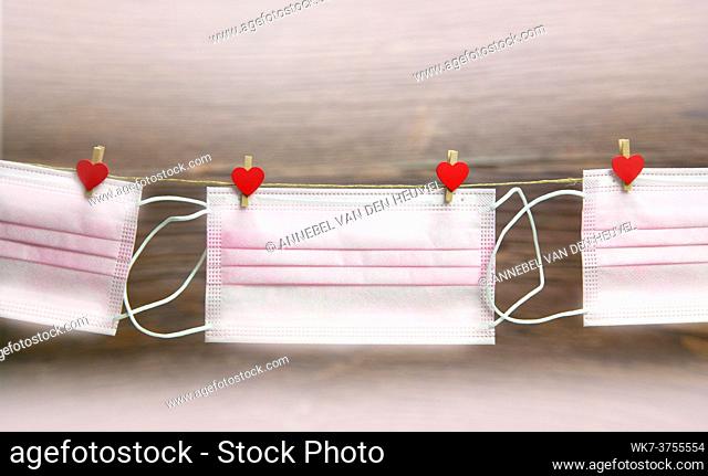 Pink protective medical mask hanging with clothes pegs in heart shape isolated on white background, Health, Covid-19 or Valentine's Day concept background love