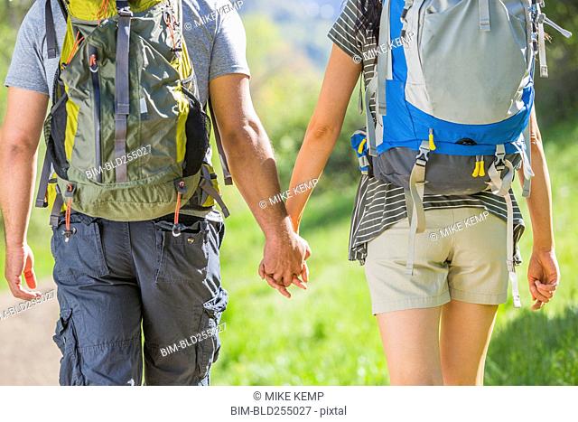 Couple carrying backpacks and holding hands
