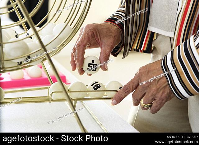 Elderly woman picking up a bingo ball