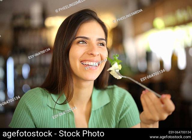 Happy woman eating lettuce at lunch smiling in a restaurant