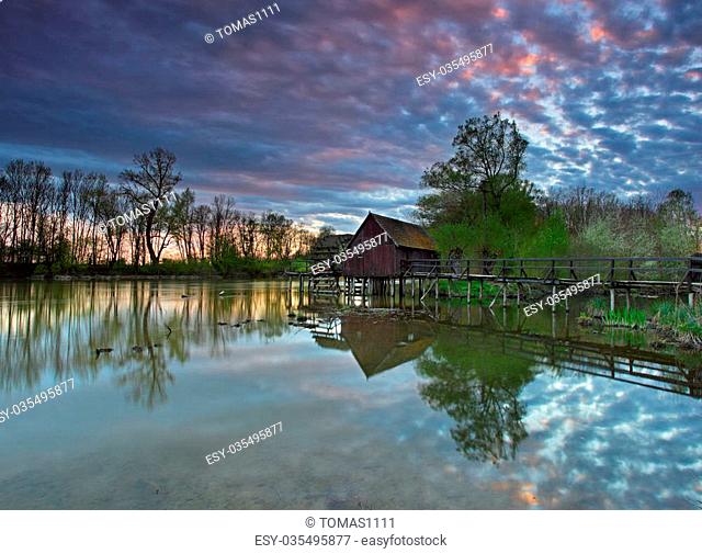 Summer landscape with river and watermill with dramatic sunset