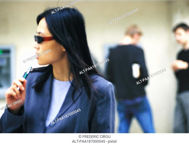 Businesswoman wearing sunglasses, holding pen