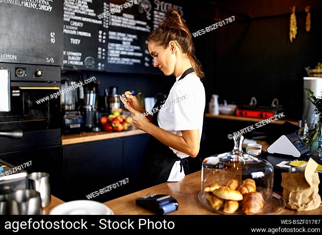 Barista writing in note pad while working at coffee shop