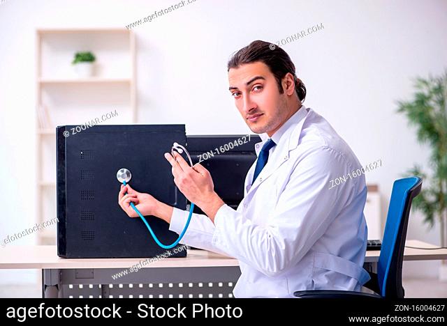 Young doctor with stethoscope repairing computer