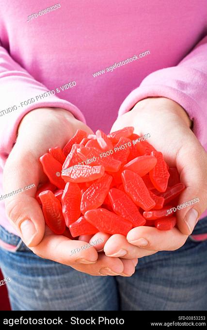 Hands holding many Swedish Fish (sweets, USA)