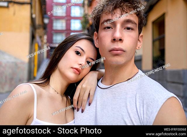 Young woman leaning on man shoulder while standing against building