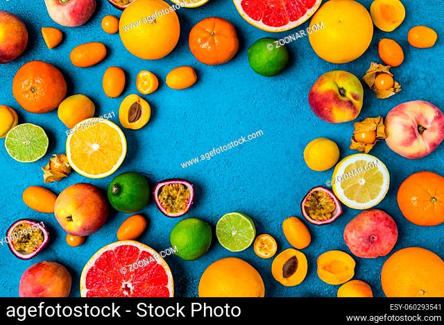 Flat lay layout of summer and citrus fruits on blue background. Healthy eating concept