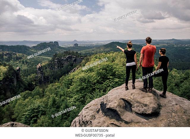 Germany, Saxony, Elbe Sandstone Mountains, friends on a hiking trip standing on rock