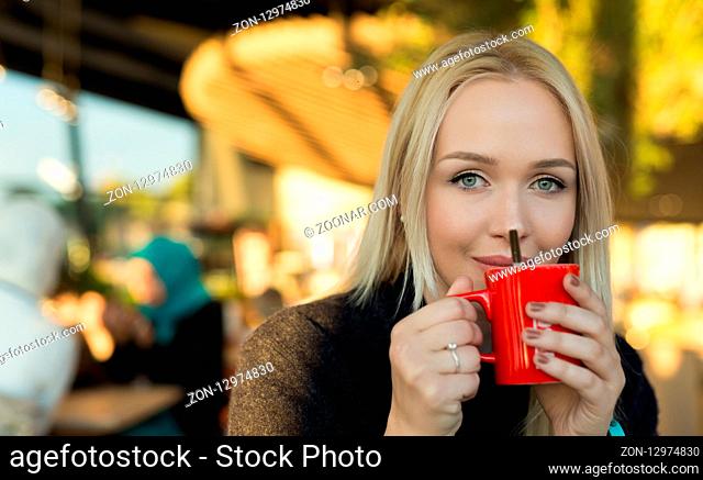 blond drinking coffee or tea in caffe shop