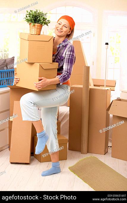 Smiling woman carrying boxes at moving house