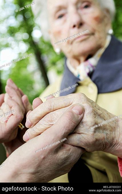 Germany, North Rhine Westphalia, Cologne, Senior woman holding hands of mature woman, close up