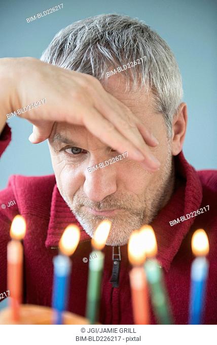 Older Caucasian man frowning at birthday cake