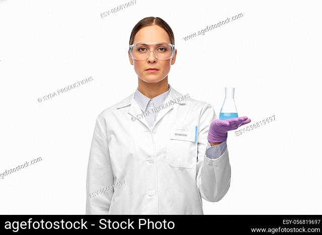female scientist in goggles with chemical in flask