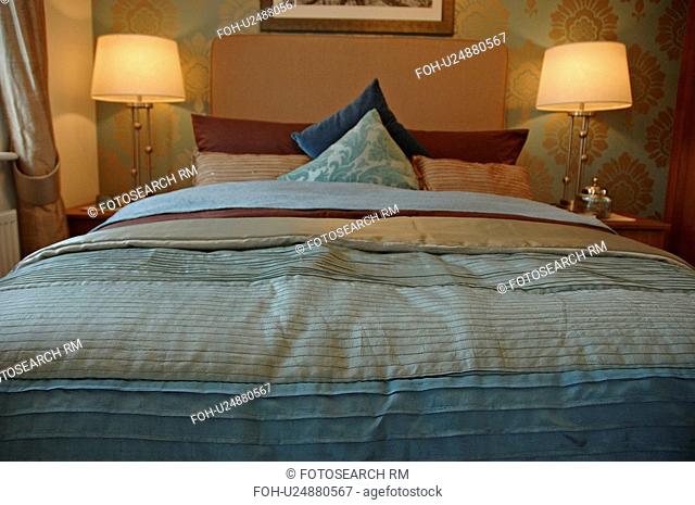 Lighted lamps on either side of bed with striped duvet in modern bedroom
