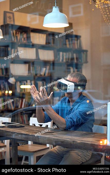Businessman gesturing with virtual reality simulator at cafe