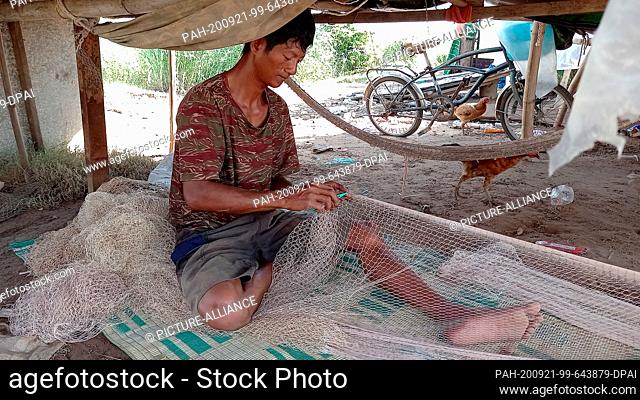 05 September 2020, Cambodia, Phnom Penh: Fisher Ho San is working on one of his fishing nets. The Mekong riverbed on the Chroy Changvar Peninsula carries hardly...