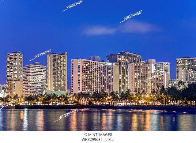Illuminated city skyline on waterfront, Honolulu, Hawaii, United States