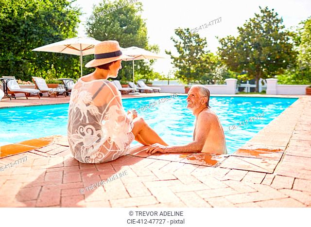 Happy mature couple relaxing at sunny resort swimming pool