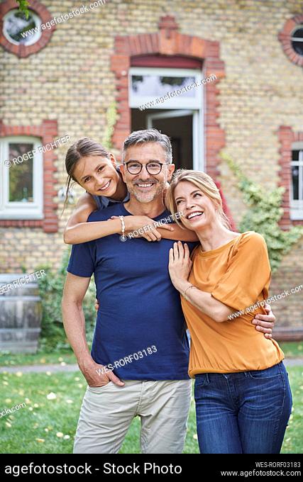 Happy daughter with parents in front of house