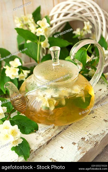 green tea with jasmine in glass teapot on wooden shabby table, vertical image