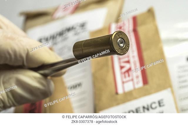Criminalistic Laboratory, Scientific police officer holds bullet tips with tweezers for ballistic analysis, conceptual image