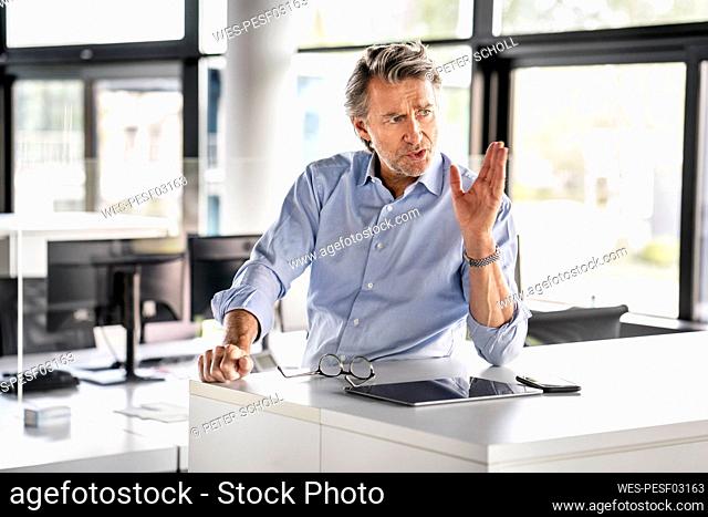 Businessman gesturing while talking at desk