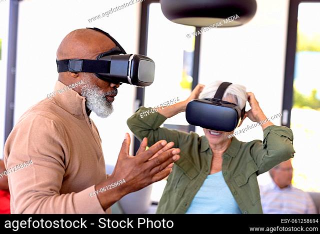 African american senior man and asian senior woman using virtual reality simulators in nursing home