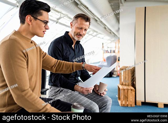 Businessman pointing at paper while working with colleague in office