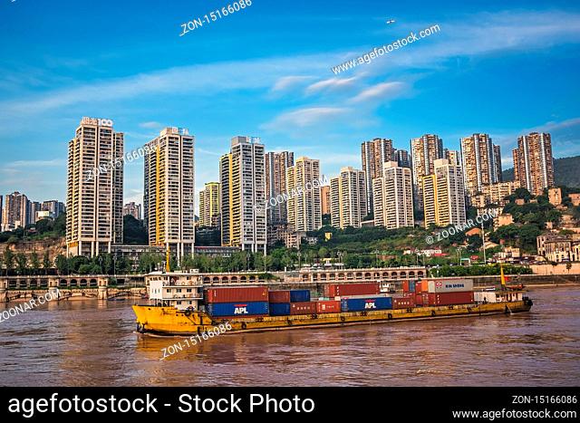 Chongqing, China - August 2019 : Huge cargo ship transporting large shipping containers departing port in Chongqing city