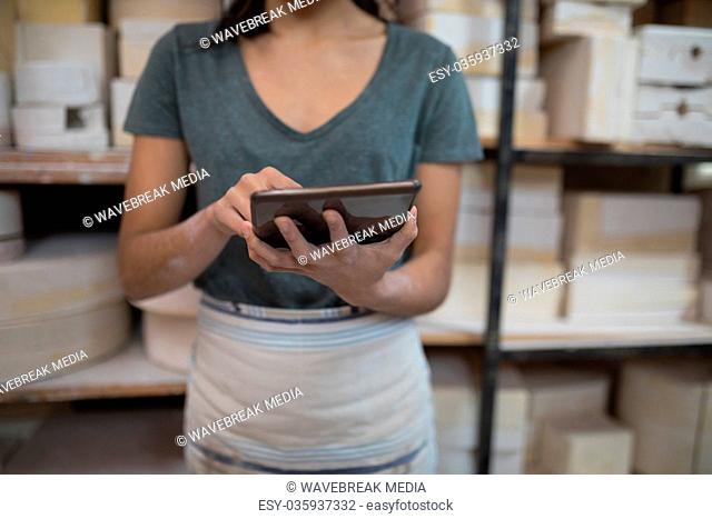 Mid section of female potter using digital tablet