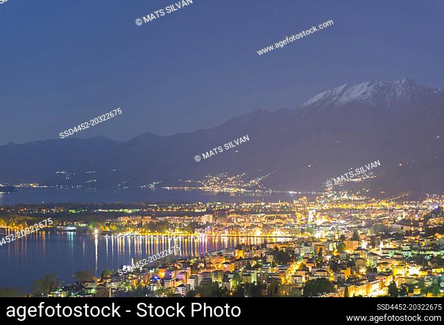 Panoramic View over an Alpine Lake Maggiore at Night with Snow-capped Mountain and Cityscape in Locarno, Switzerland