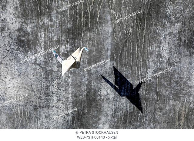 Origami crane flying, concrete wall