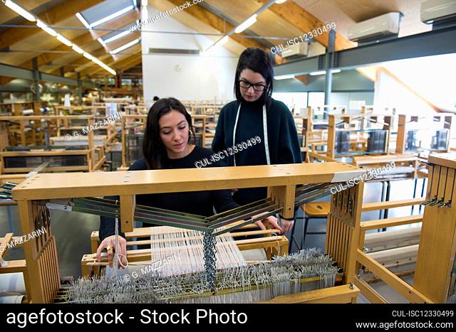 Students weaving with loom in textile workshop