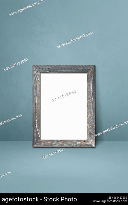 Wooden picture frame leaning on a grey wall. Blank mockup template