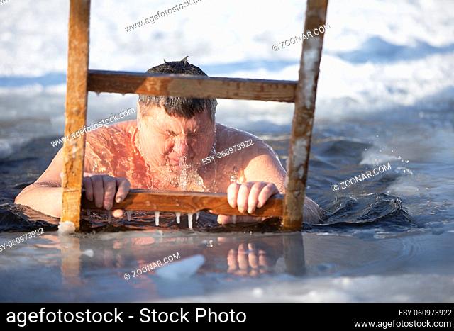 A man plunges into an ice-hole during the winter festival of the baptism of Jesus. A man swims in the ice-hole in winter. Walrus people
