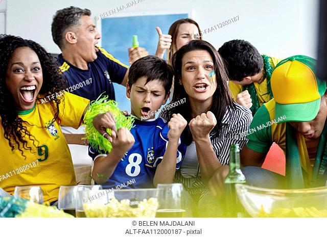 Brazilian football fans celebrating victory while watching match at home